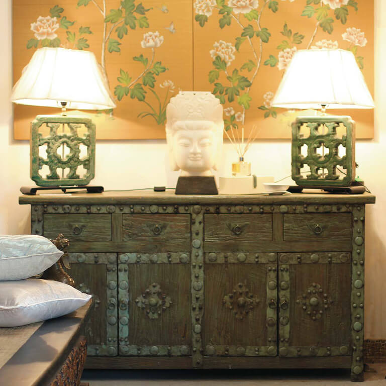 A pair of lamps and Buddha ornament on an antique cabinet