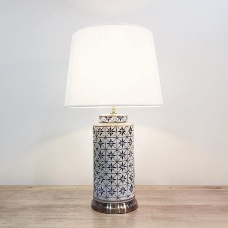 A tall cylindrical ceramic table lamp with a modern blue & white print