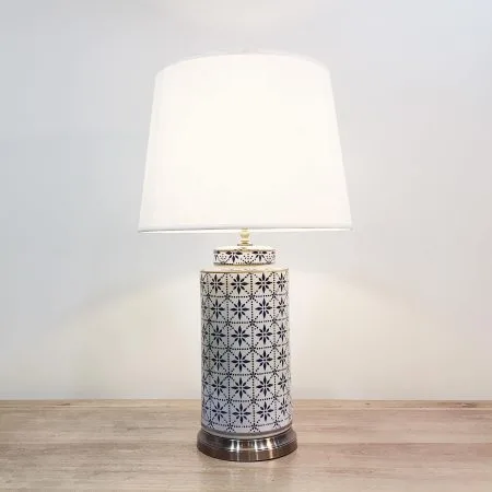 A tall cylindrical ceramic table lamp with a modern blue & white print