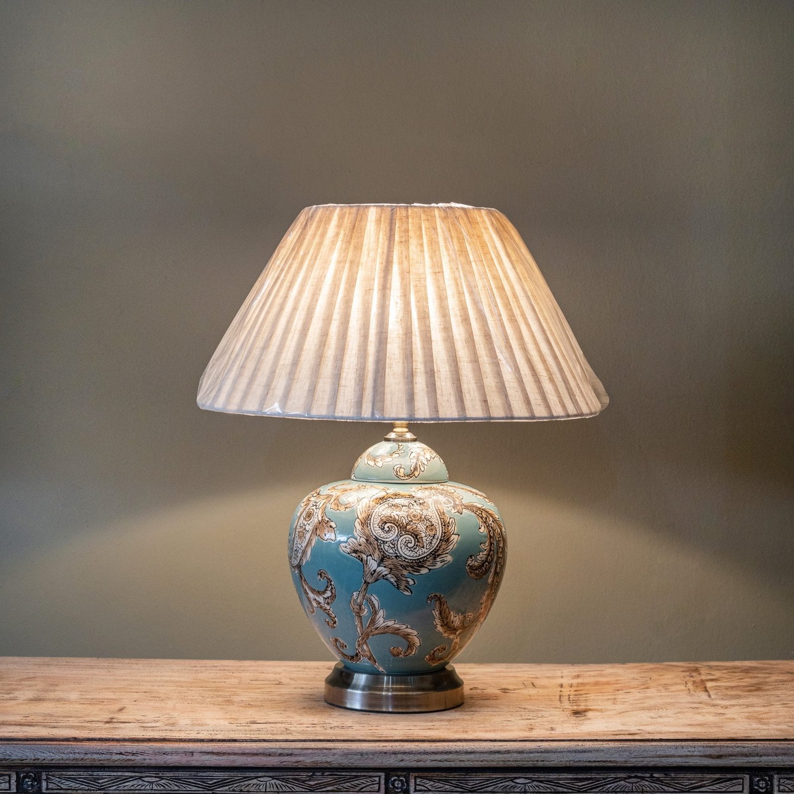 Round teal ceramic table lamp with light brown/beige floral designs