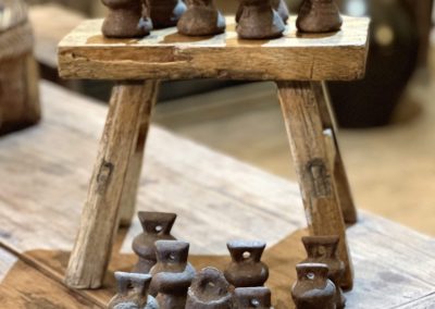 a group of antique iron weights and wooden rustic stool