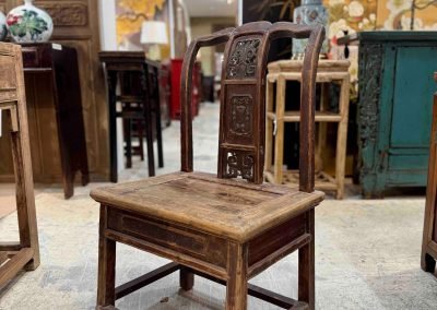 A small light brown vintage chinese sedan chair with carving on the back splat