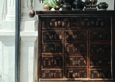 Chinese antique medicine cabinet from Shanxi. This has rectangular drawers and paper labels. The morning light coming in adds warmth and depth to the picture