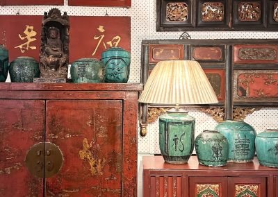 Chinese antique furniture. A red & gold lacquered Shanxi cabinet, with a carved slim red sideboard on the right. The wall is full of chinese vintage carvings and panels