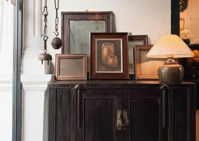 A chinese antique dark aubergine walnut wood cabinet with wooden pictures frames on it